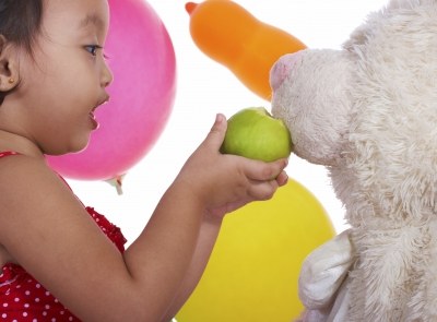 niña alimentando a osito con manzana